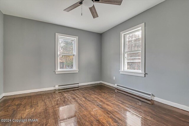 unfurnished room featuring baseboards, baseboard heating, and wood finished floors