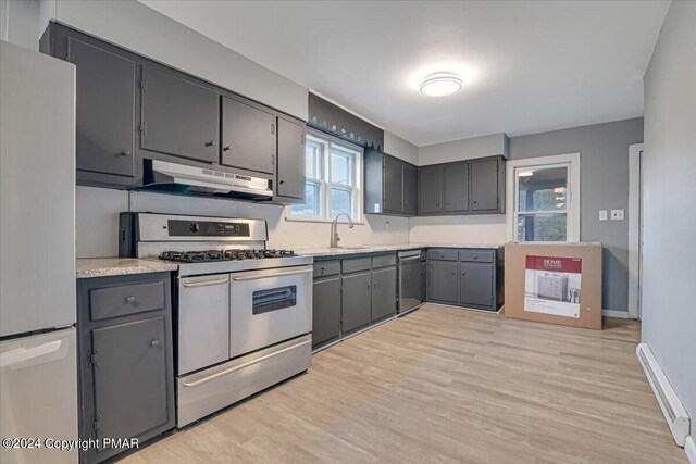 kitchen featuring freestanding refrigerator, light countertops, gray cabinetry, under cabinet range hood, and double oven range