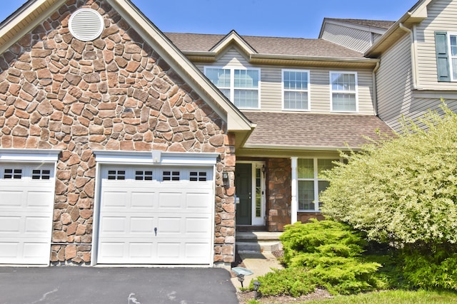 1785 Big Ridge Dr, East Stroudsburg, PA 18302 - view of front facade featuring stone siding, roof with shingles, an attached garage, and driveway