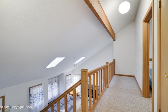 corridor with light carpet, vaulted ceiling with skylight, baseboards, and an upstairs landing