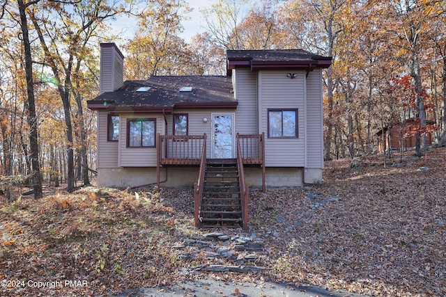 back of property with a deck, a chimney, and stairs