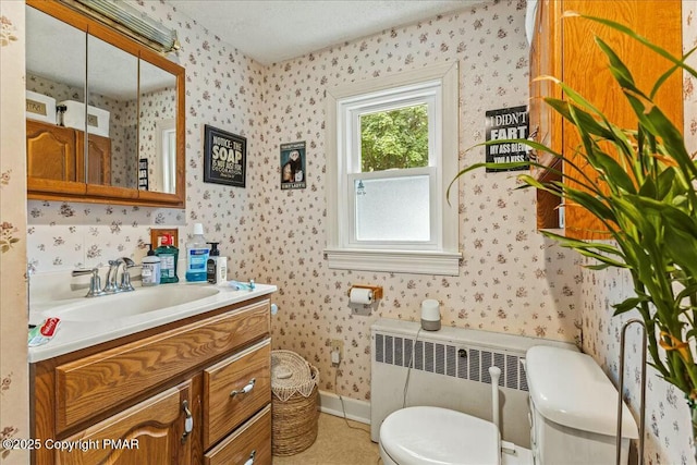 half bathroom with wallpapered walls, radiator heating unit, baseboards, and vanity