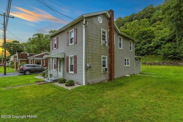 view of property exterior featuring cooling unit, a lawn, and a chimney