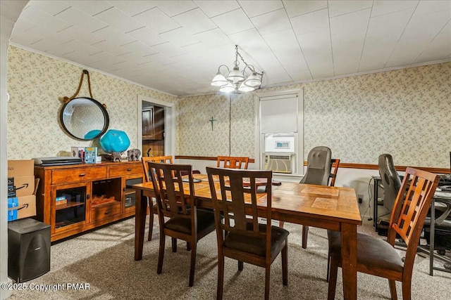 carpeted dining space featuring a notable chandelier, ornamental molding, cooling unit, and wallpapered walls