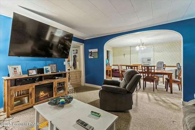 carpeted living room with arched walkways, baseboards, wallpapered walls, a glass covered fireplace, and an inviting chandelier