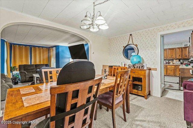 dining room featuring ornamental molding, light carpet, an inviting chandelier, and wallpapered walls