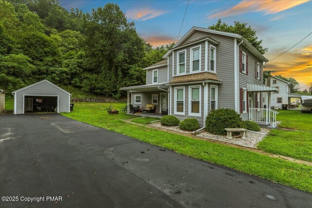 view of front of home featuring a garage, an outdoor structure, and a lawn