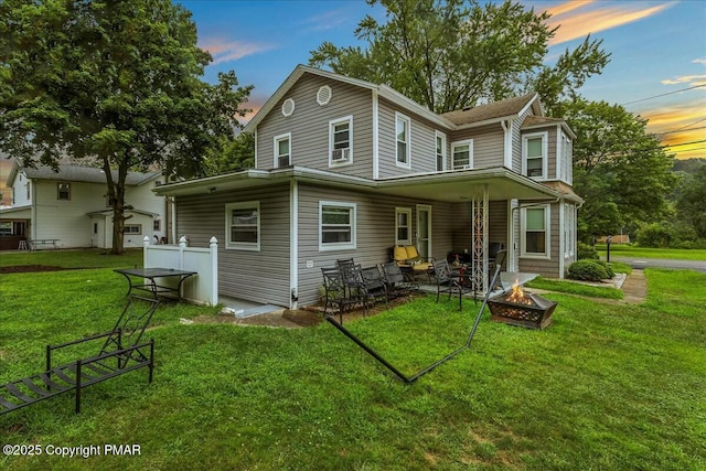 back of house with a fire pit and a yard