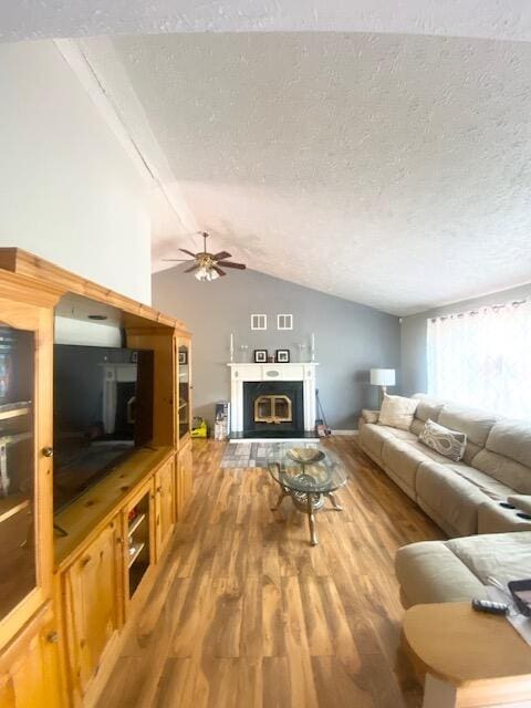 1293 Winding Way, Tobyhanna, PA 18466 - living room with a textured ceiling, wood finished floors, a ceiling fan, vaulted ceiling, and a glass covered fireplace
