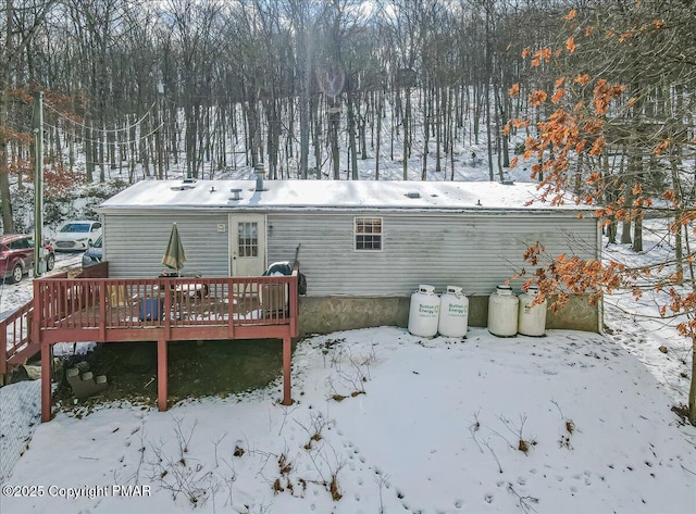 snow covered back of property featuring a deck