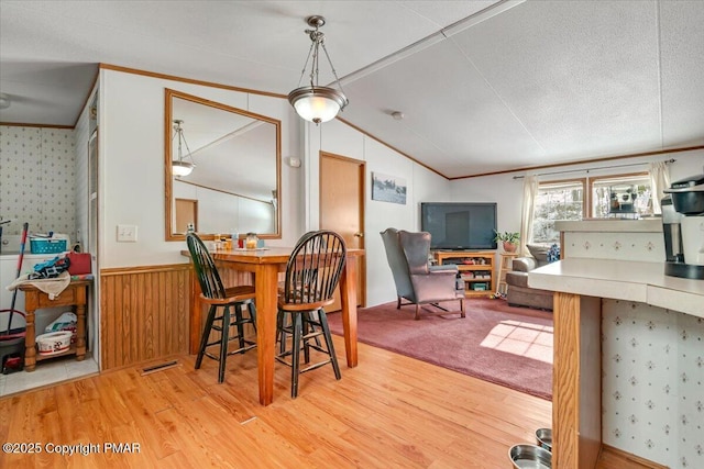 dining space featuring lofted ceiling, a wainscoted wall, crown molding, and wood finished floors