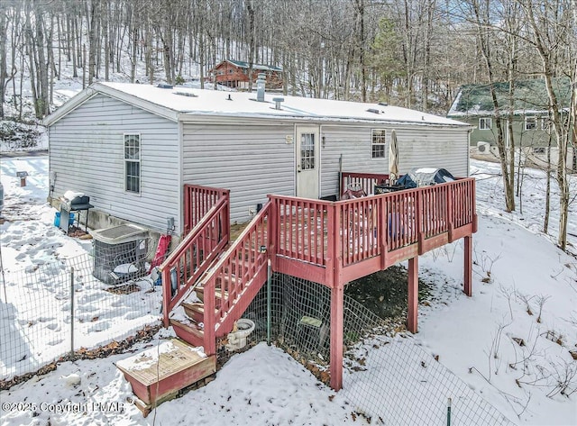 snow covered back of property featuring a wooden deck and central air condition unit