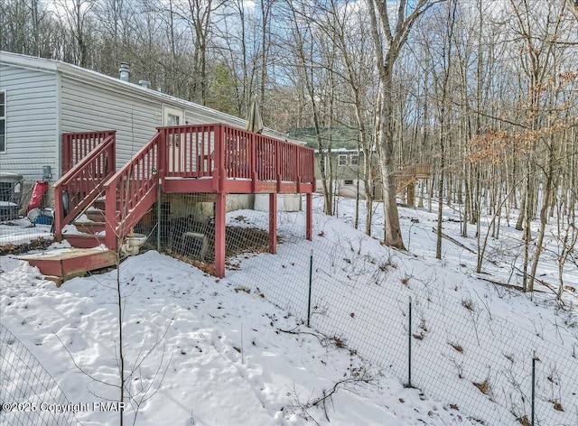 snowy yard featuring fence, a deck, and stairs