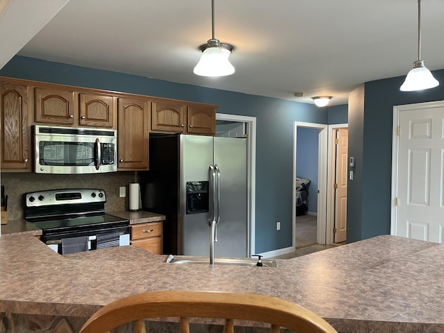 kitchen featuring stainless steel appliances, a sink, pendant lighting, decorative backsplash, and brown cabinets