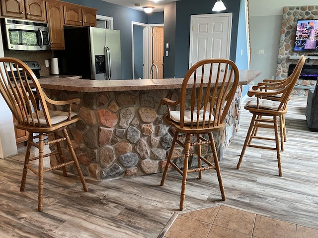 bar area featuring stainless steel appliances, a sink, and light wood finished floors