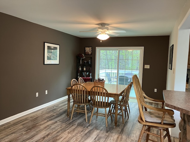 dining space with wood finished floors, a ceiling fan, and baseboards