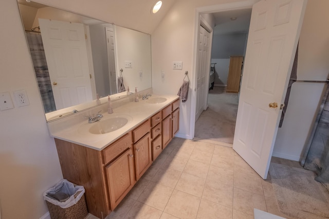 full bathroom with double vanity, lofted ceiling, tile patterned floors, and baseboards