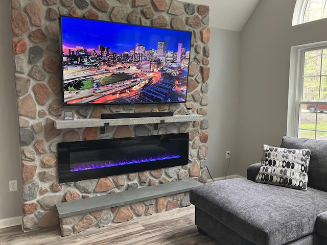 detailed view of a fireplace, wood finished floors, and baseboards