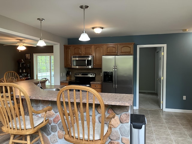 kitchen with appliances with stainless steel finishes, hanging light fixtures, a breakfast bar, and tasteful backsplash