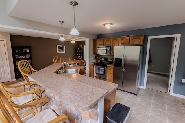 kitchen featuring stainless steel appliances, a sink, light countertops, baseboards, and light tile patterned flooring