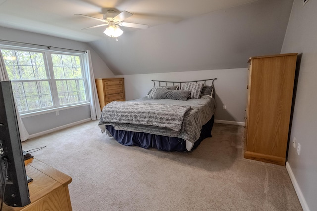 bedroom featuring vaulted ceiling, light colored carpet, baseboards, and a ceiling fan