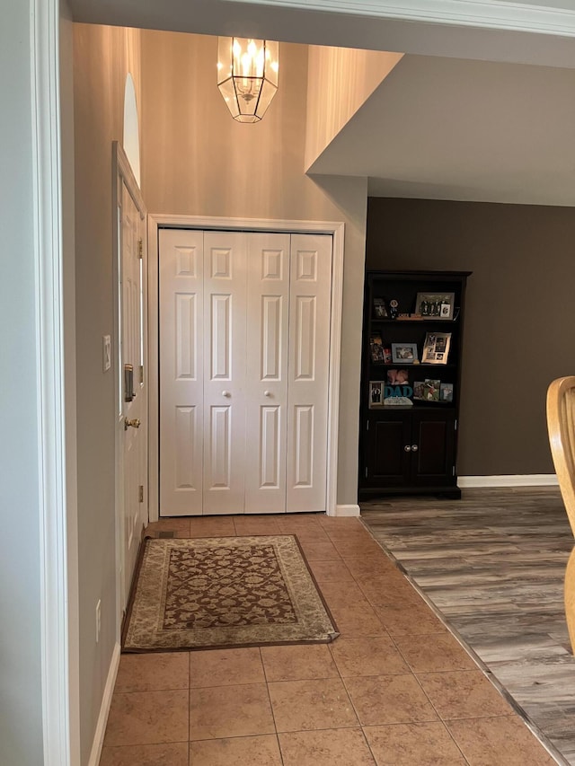 foyer entrance featuring tile patterned floors, baseboards, a chandelier, and arched walkways