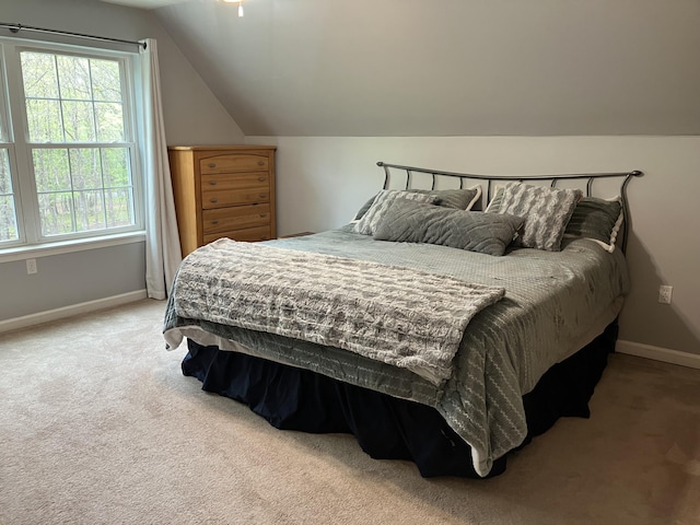 carpeted bedroom featuring baseboards and lofted ceiling