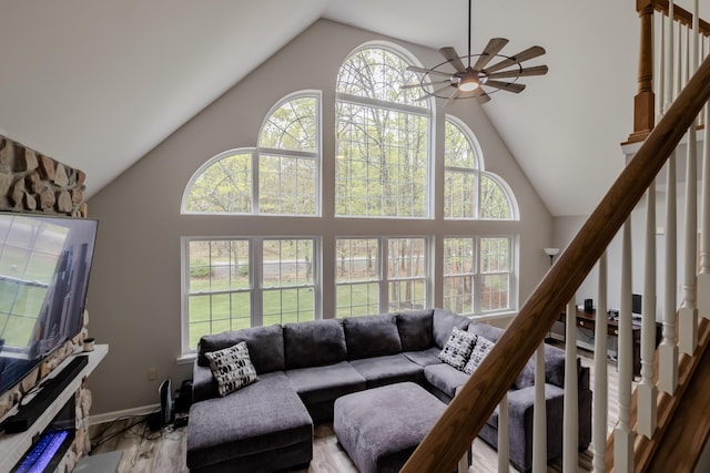 living room with high vaulted ceiling, ceiling fan, stairs, and baseboards