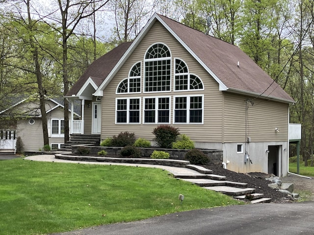 view of front of house featuring a front yard, a garage, and roof with shingles