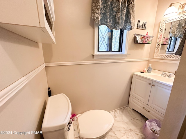 half bath featuring toilet, marble finish floor, and vanity