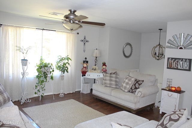 living area with ceiling fan with notable chandelier, visible vents, and wood finished floors