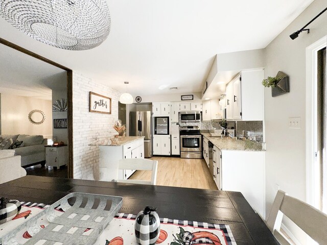 kitchen featuring visible vents, light wood-style flooring, a sink, stainless steel appliances, and backsplash