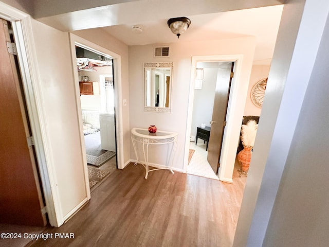 hallway featuring baseboards, visible vents, and wood finished floors