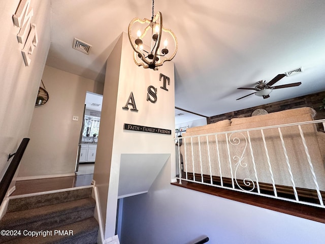 stairway featuring visible vents, baseboards, and ceiling fan with notable chandelier