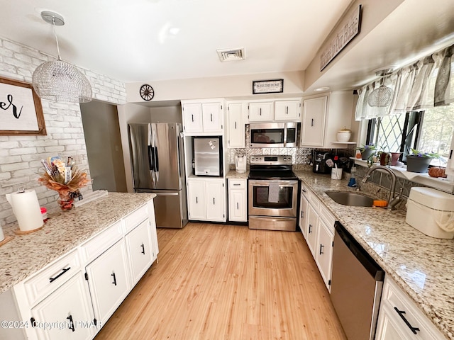 kitchen with visible vents, appliances with stainless steel finishes, white cabinetry, a sink, and light wood-type flooring