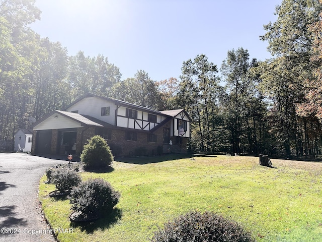 view of front of house featuring an attached garage, brick siding, aphalt driveway, and a front yard