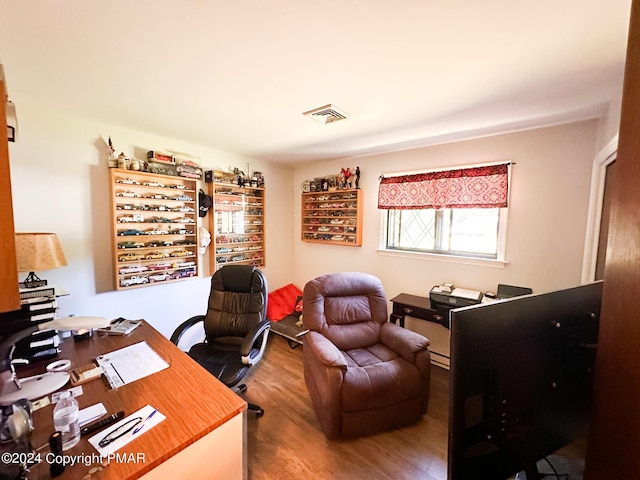 office with baseboard heating, wood finished floors, and visible vents