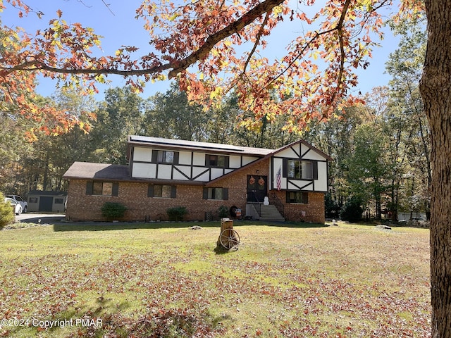 tudor-style house with brick siding and a front yard