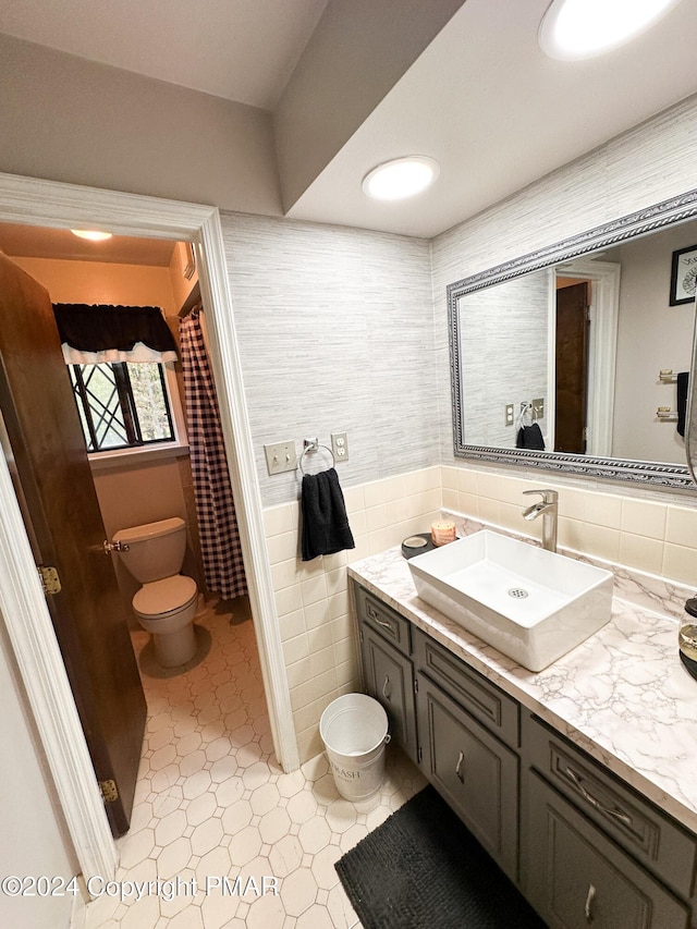 bathroom with toilet, tile walls, and vanity