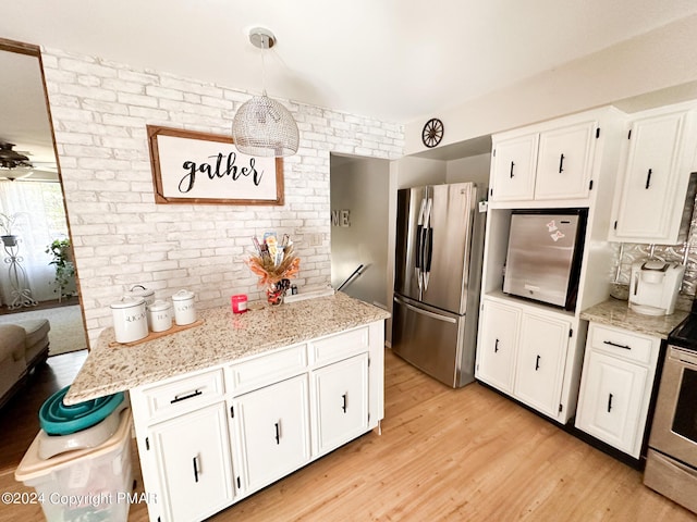 kitchen featuring white cabinets, light wood-style flooring, light stone counters, and stainless steel appliances