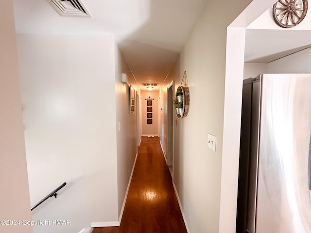 hall with baseboards, visible vents, and wood finished floors