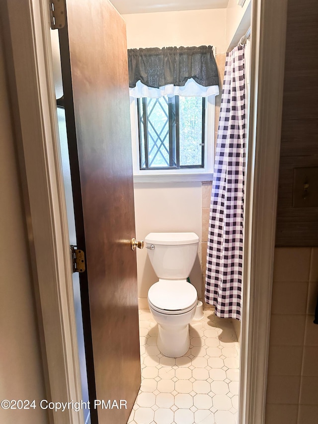 full bathroom with toilet, a shower with curtain, and tile patterned flooring