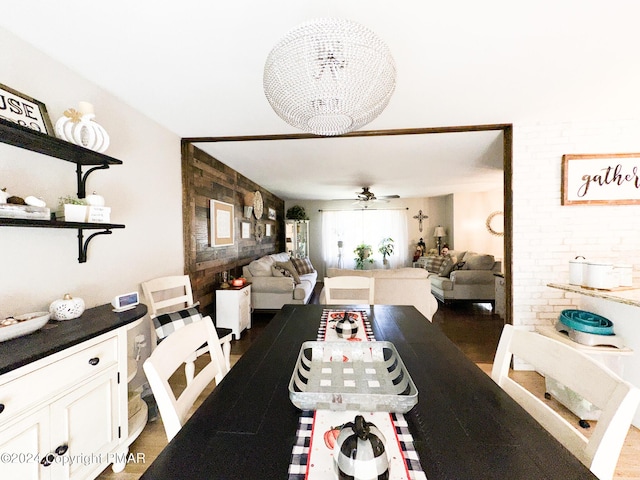 dining area with ceiling fan with notable chandelier and brick wall