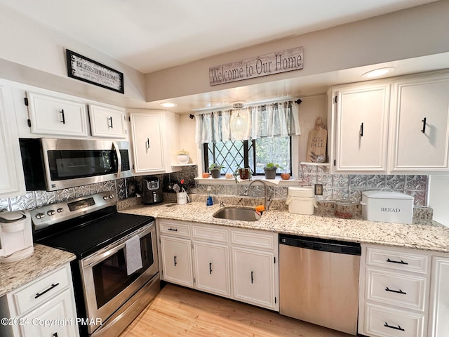 kitchen featuring stainless steel appliances, white cabinets, a sink, and tasteful backsplash