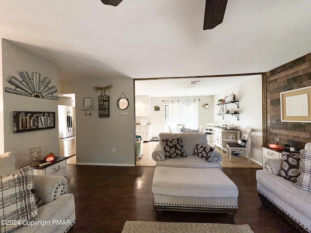 living area featuring wood walls, ceiling fan, and wood finished floors