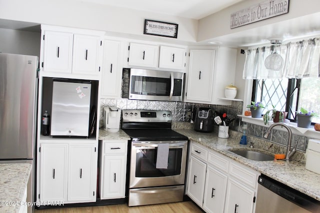 kitchen featuring white cabinetry, appliances with stainless steel finishes, tasteful backsplash, and a sink