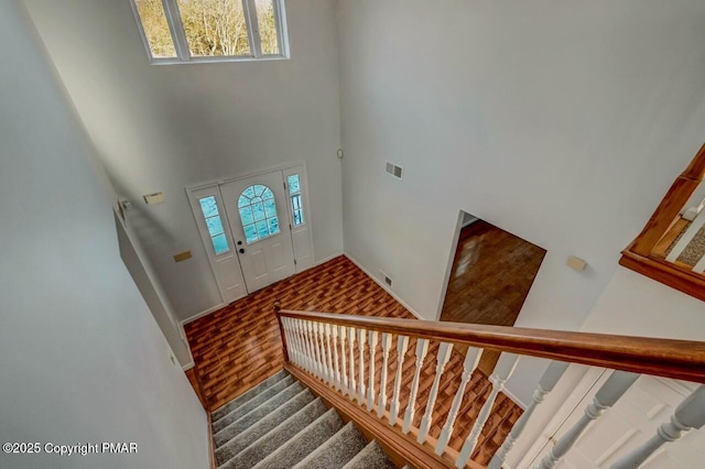 foyer with stairs, wood finished floors, visible vents, and a healthy amount of sunlight