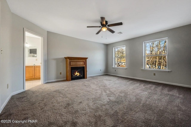 unfurnished living room featuring carpet flooring, a glass covered fireplace, visible vents, and baseboards