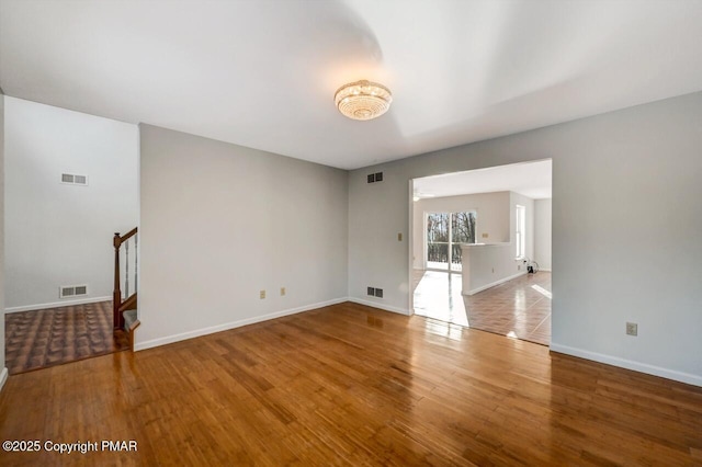 spare room with stairway, baseboards, visible vents, and wood finished floors