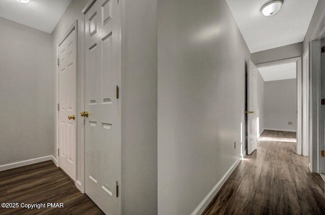 hall with dark wood-type flooring and baseboards